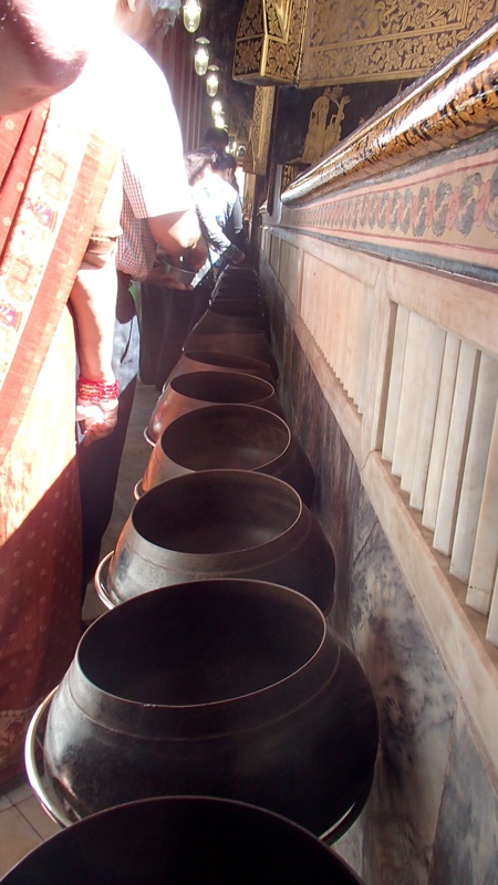 The entire hall was filled with an irritating rattling sound, as we walked around the back of the Buddha,Mae found out why: people were changing bills for coins and dropping them into about 100 alms bowls for good luck.